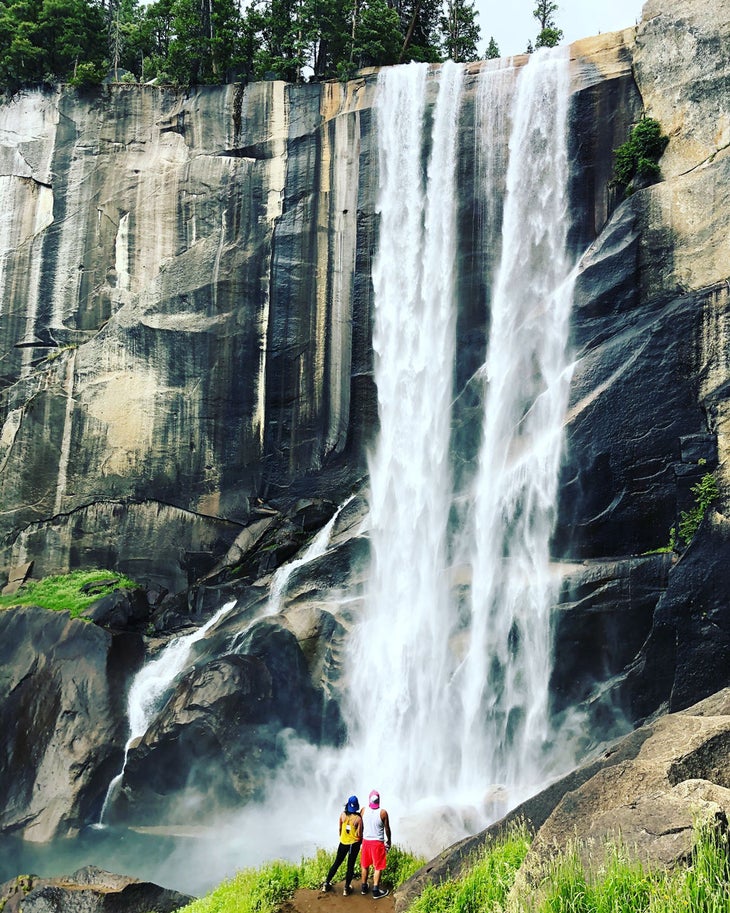 Mist Trail hikers standing underneath Vernal Fall in Yosemite